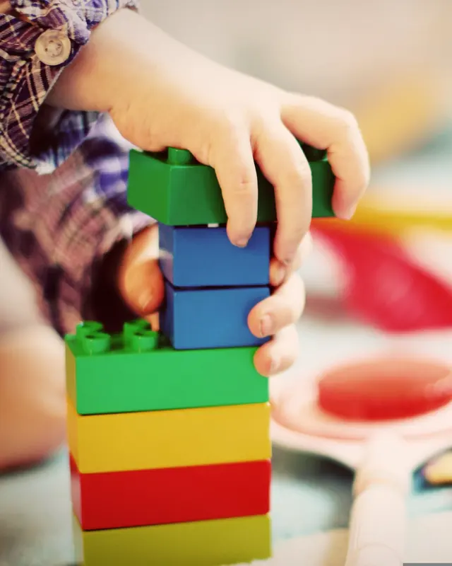 Little hands stacking colorful building blocks