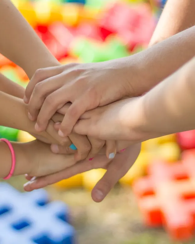 School-age kids stacking hands as a team
